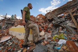 A Ukrainian service member looks at the rubble of a school that was destroyed during a missile attack on the outskirts of Kharkiv, Ukraine.