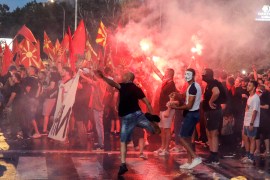 People light flares and throw eggs and stones on the foreign ministry building during a protest in Skopje on July 5 [Boris Grdanoski/AP]