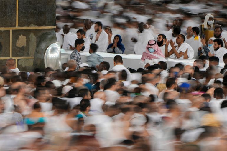 low shutter speed, Muslim pilgrims pray as others circumambulate around the Kaaba