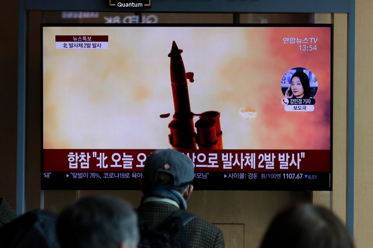 People watch a TV screen showing a file image of North Korea's firing of projectiles at the Seoul Railway Station in Seoul, South Korea in 2020. North Korea appeared to have conducted artillery firing drills on Sunday, July 10, 2022, South Korea said, days after the United States deployed sophisticated fighter jets to South Korea [File: Lee Jin-man/AP]