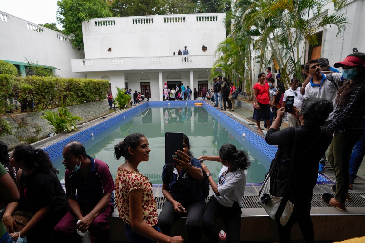 People sit by the swimming pool as they throng President Gotabaya Rajapaksa's official residence