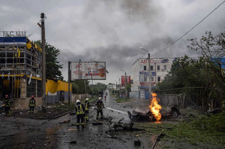 Rescue workers put out the fire of a destroyed car after a Russian attack in Kharkiv, Ukraine.