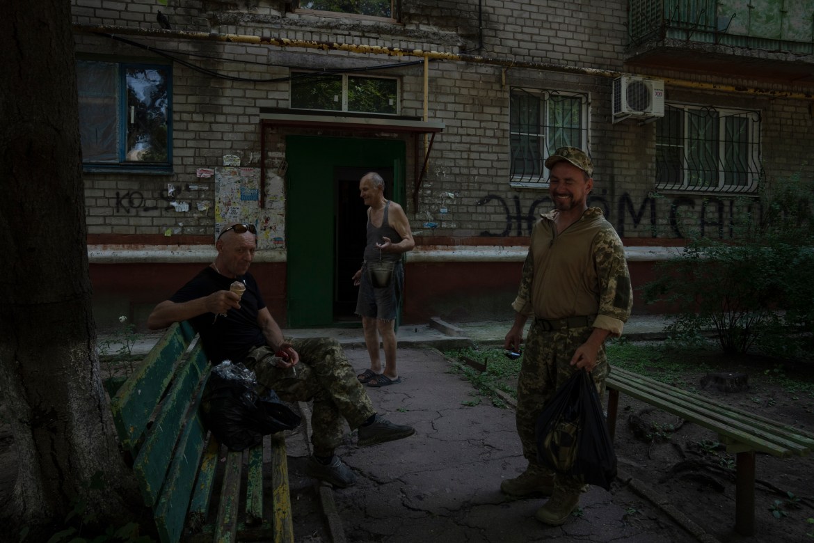 Soldiers rest and eat ice-cream on benches in front of the apartment building Seventy-year-old pensioner Valerii Ilchenko