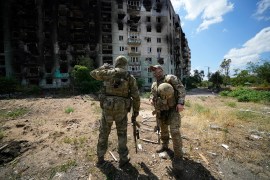 Russian soldiers talk to each other near an apartment building damaged during fighting in Severodonetsk, Ukraine.