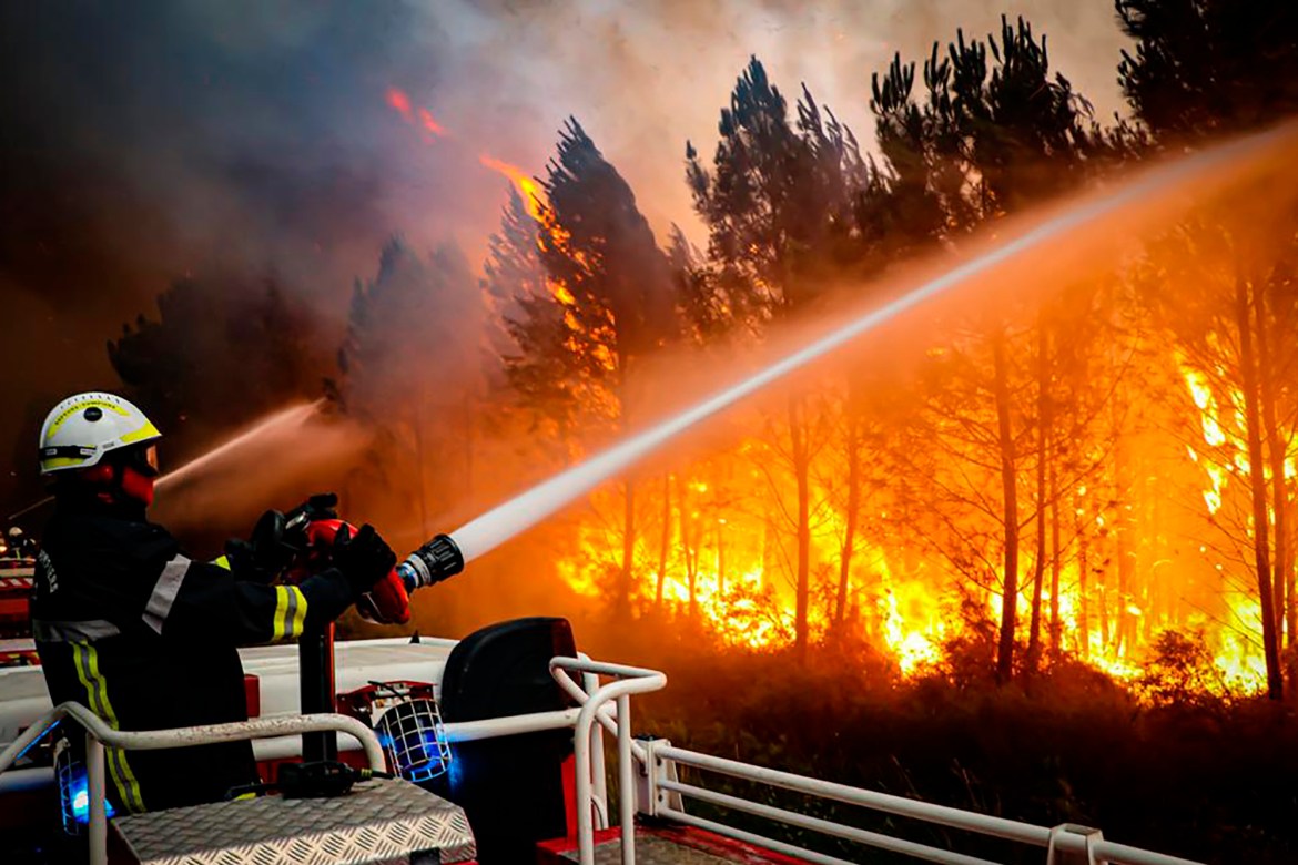 firefighters using hose to fight a wildfire near Landiras, southwestern France,