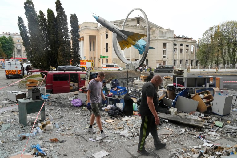 People sort through the wreckage and belongings after a Russian missile attack on Vinnytsia, in front of a large older building and a
