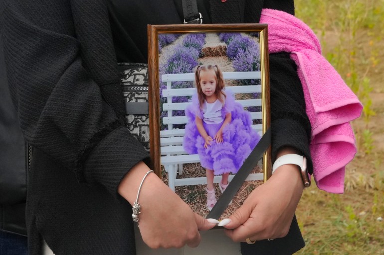 A woman carries a portrait of Liza, 4-year-old girl killed by Russian attack, during a funeral ceremony in Vinnytsia, Ukraine, Sunday, July 17, 2022. Wearing a blue denim jacket with flowers, Liza was among 23 people killed, including two boys aged 7 and 8, in Thursday's missile strike in Vinnytsia. Her mother, Iryna Dmytrieva, was among the scores injured.