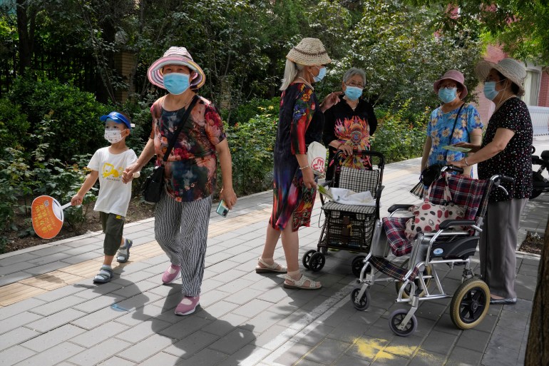 Women and children wear face masks as they meet on the street in Beijing