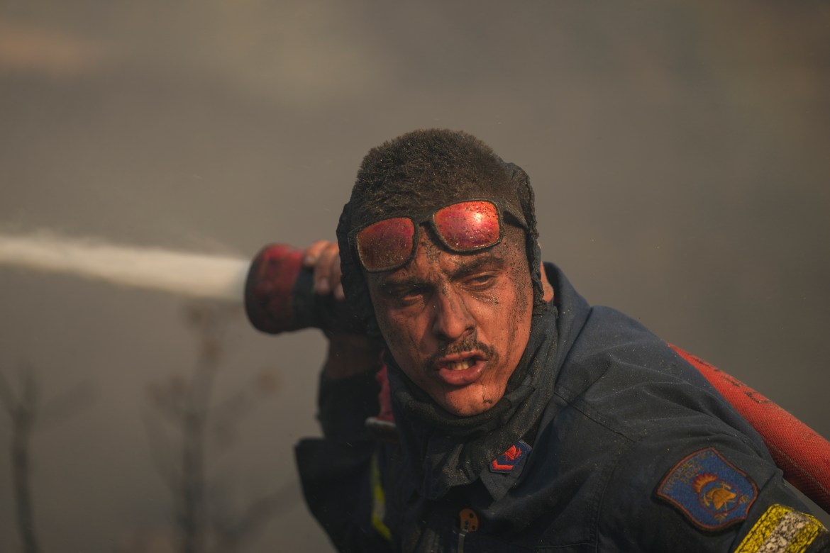A firefighter sprays water in the Mount of Penteli