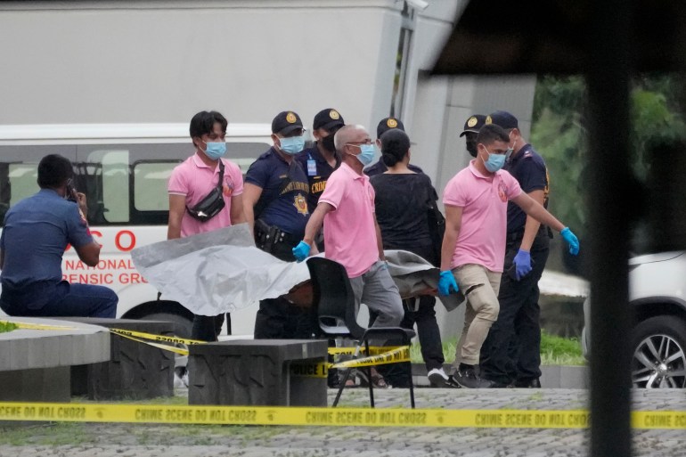 A victim's body is removed from the scene of a shooting at the Ateneo de Manila University in Quezon, Philippines