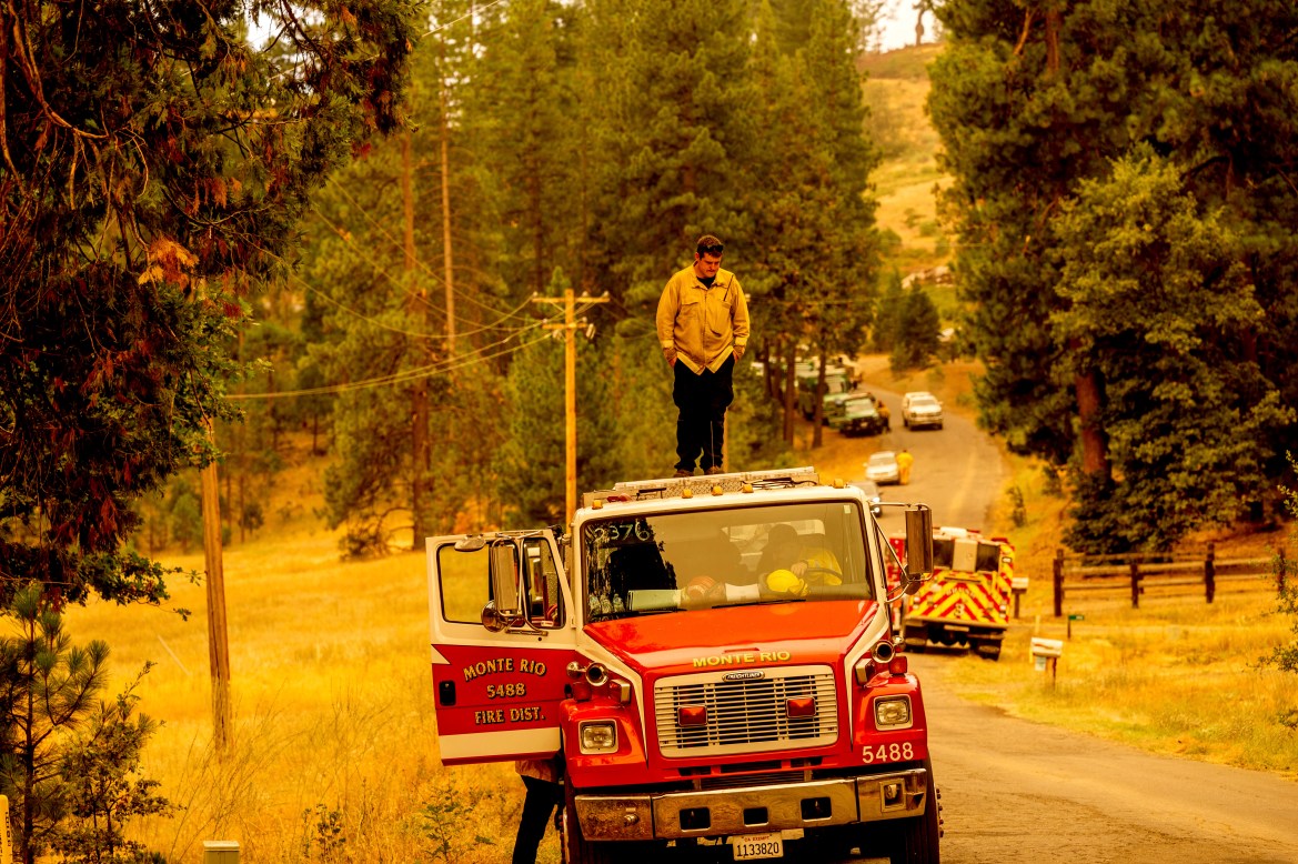 A firefighter stands atop a fire engine shortly after coming on duty to battle the Oak Fire