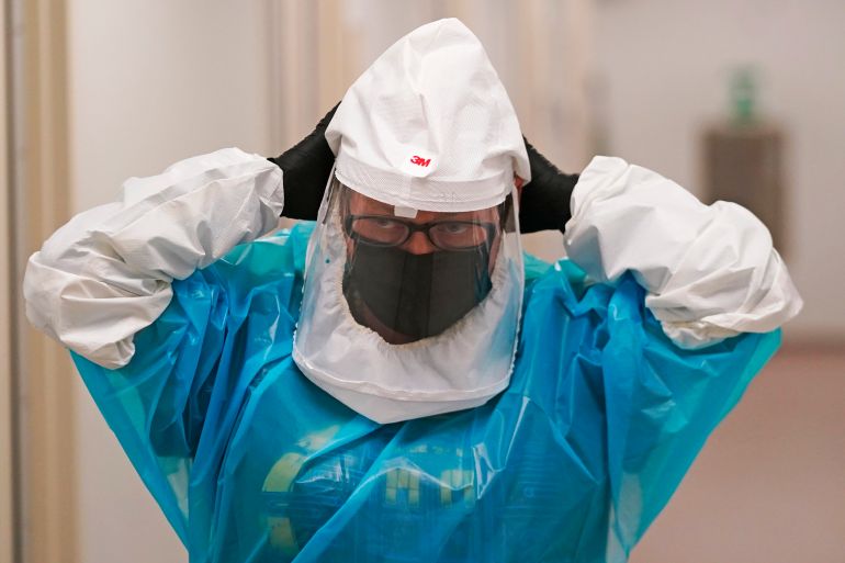 A microbiologist adjusts her power air purifying respirator during a demonstration on how labs test for the monkeypox virus