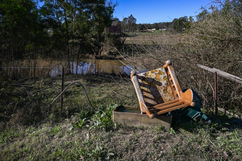 Une chaise endommagée repose sur l'herbe couverte de boue de la terre de Nena après le recul des inondations.