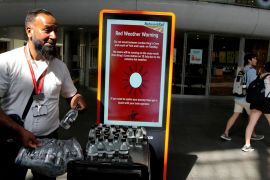 A railway worker hands out bottles of water at a train station in London
