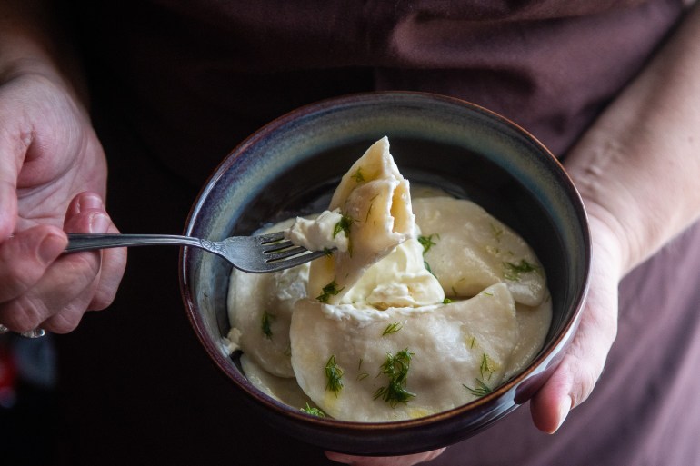 Photo of a pair of hands holidng a bowl of dumplings