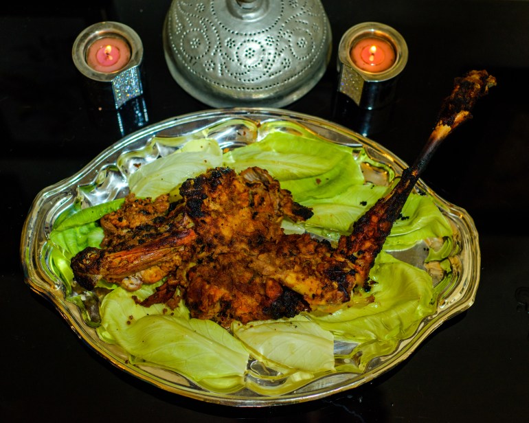 A view of the cooked raan kabab on a silver platter on a bed of lettuce