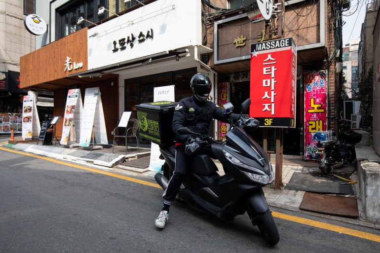 A food delivery courier rides a motorcycle carrying a customer's order outside a restaurant in the Gangnam district of Seoul, South Korea, on Monday, March 3, 2020. 