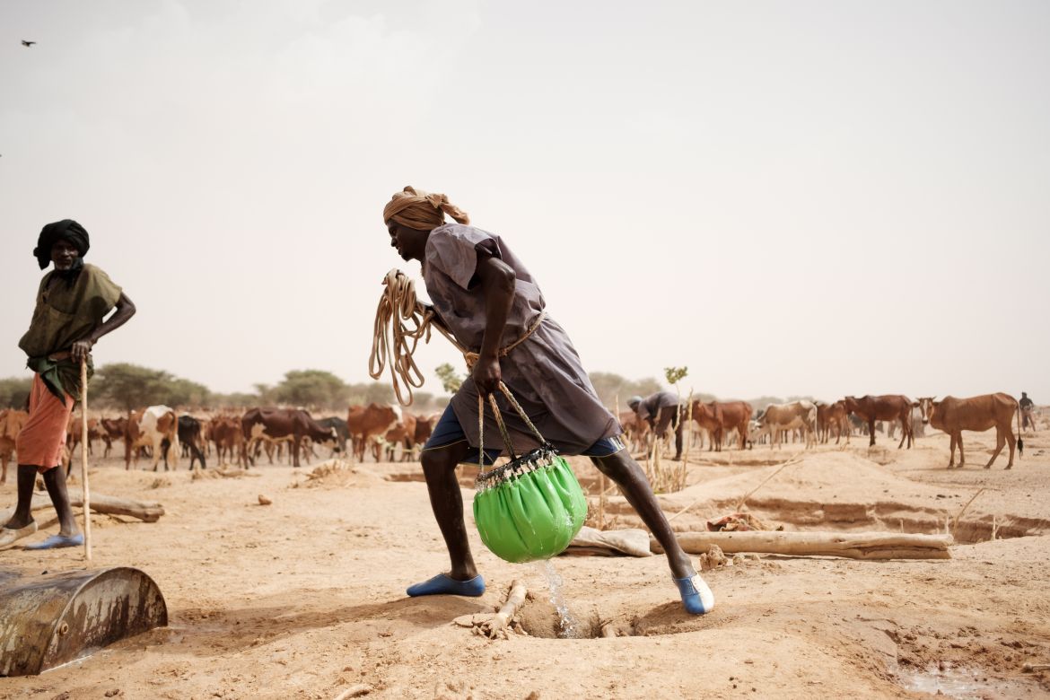 Si collects water from a hand dug well on a dried river bed