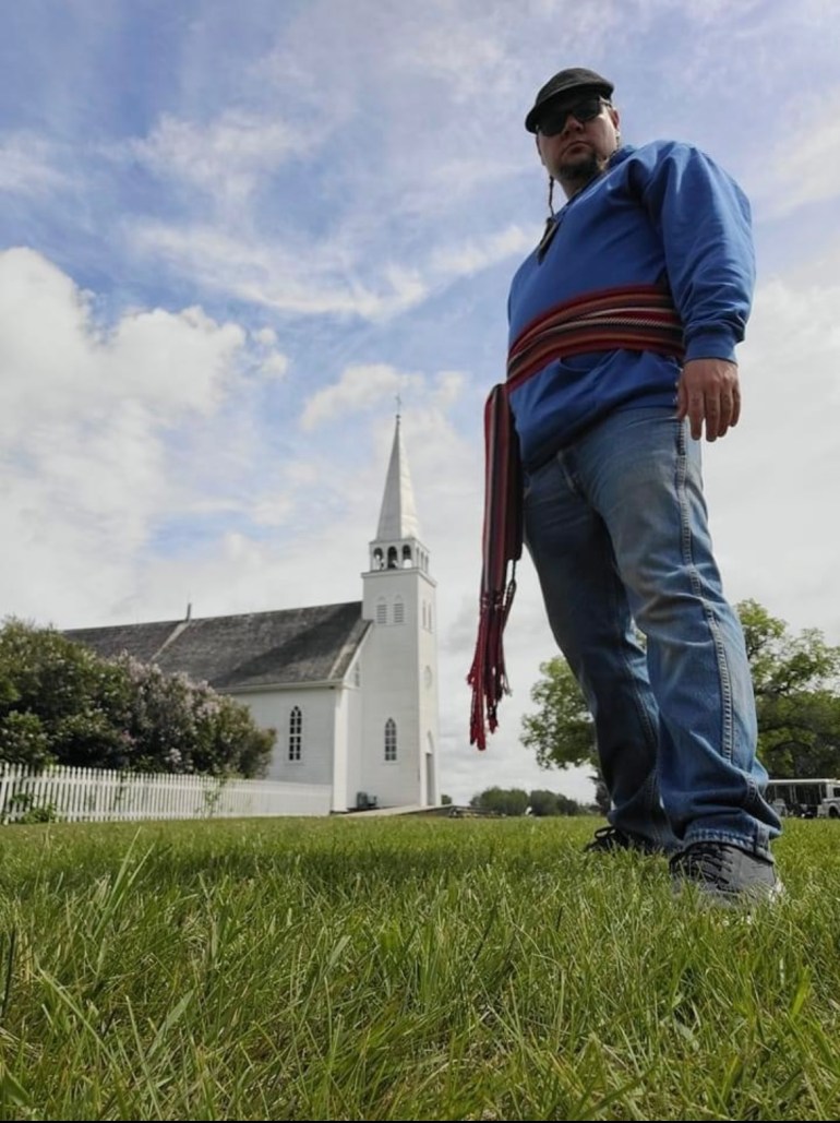 A photo of John Brady Macdonald standing in front of a church,
