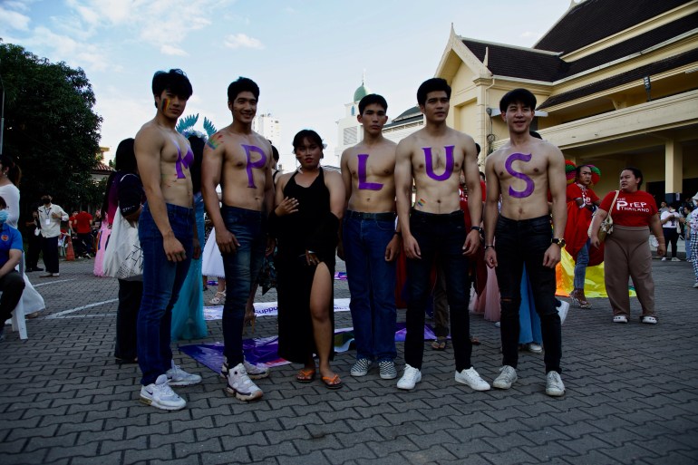Shirtless young men from Mplus pose for a group photo as they take part in the Pride parade that they organised in Chiang Mai, 