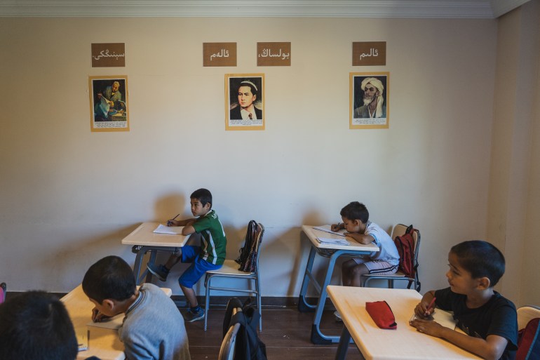 A photo of a classroom with 3 photos of famous Uyghur poets and writers on the wall.