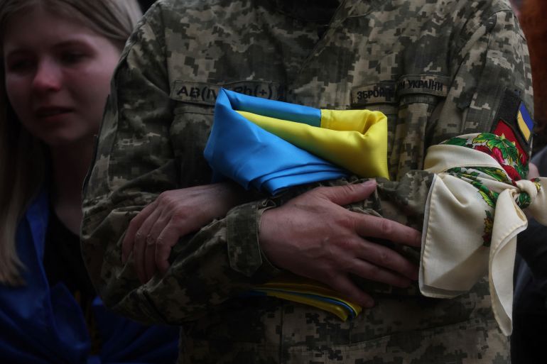 A father holds a Ukrainian flag during his son's funeral in Kyiv, Ukraine.