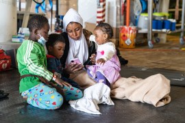 Libyan Search and Rescue Region, 23 April 2022, Sadia* (centre) and her children play with her phone on the deck of the Geo Barents. There is no cell signal or internet onboard for survivors, so they are unable to make phone calls.