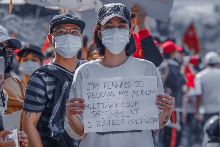 Thazin and Zeya at a protest with Thazin holding a placard in English reading 'I'm planning to release my album. Military coup destroy it. I reject coup d'etat' 