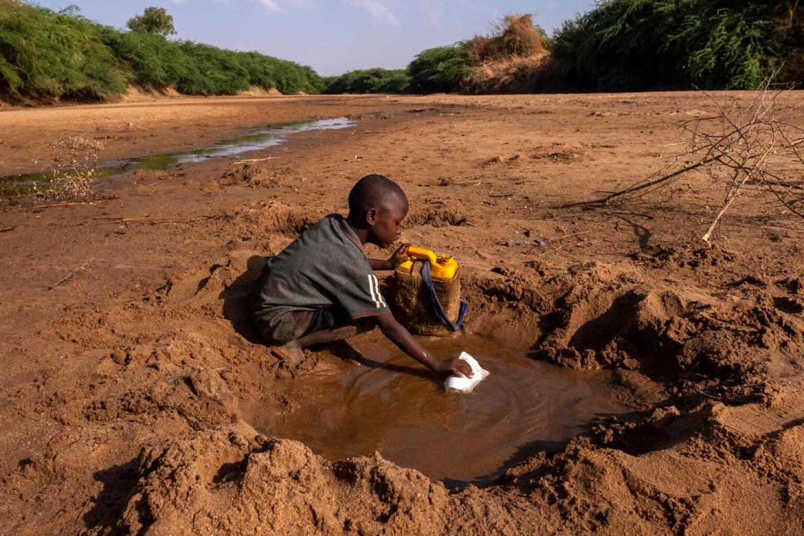 A young boy collects what little water he can from a dried up river due to severe drought.Dollow Somalia.