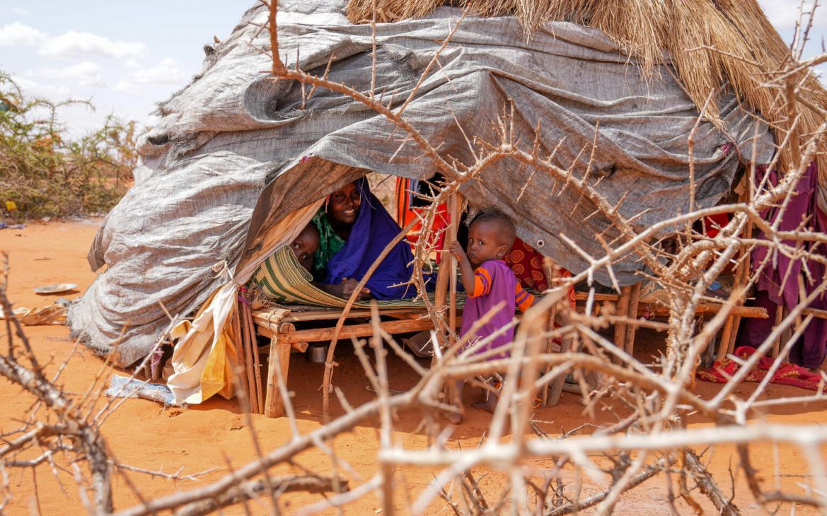 Little Gedi plays with his baby sister and mother inside a makeshift tent at Kaharey IDP camp in Dollow, Somalia.