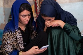 Two Afghan sisters look at a picture of their murdered sister, who they grieve