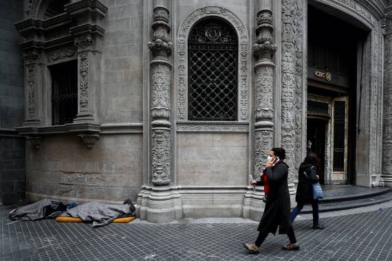 Pedestrians walk past people sleeping outside a bank, in Buenos Aires’ financial district, Argentina