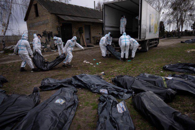 Voluntarios cargan los cuerpos de los civiles asesinados en Bucha en un camión para llevarlos a la morgue para su investigación, en las afueras de Kiev, Ucrania, el martes 12 de abril.