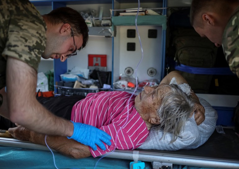 Ukrainian military paramedics attend resident Nina Trofimenko, 86, who was wounded during shelling near the frontline in the Donbas