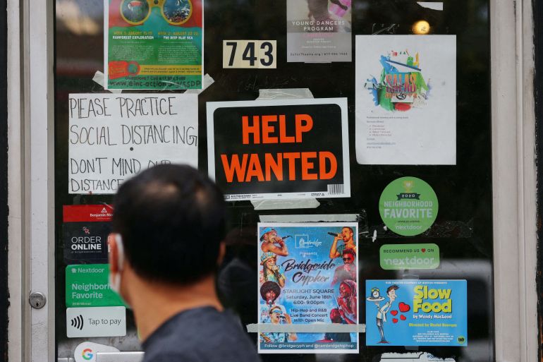A pedestrian passes a "Help Wanted" sign in the door of a hardware store in Cambridge, Massachusetts, U.S