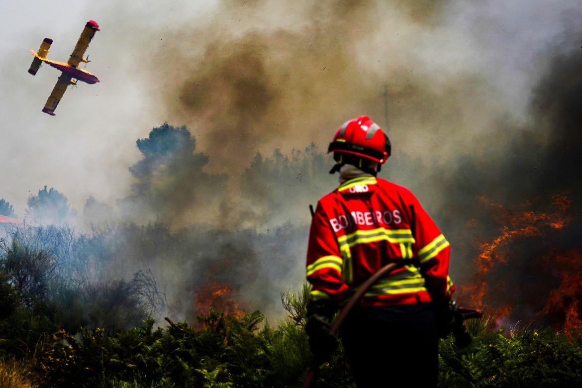 A firefighter fights the flames surrounding Ancede village during a wildfire in the municipality of Baiao, North of Portuga