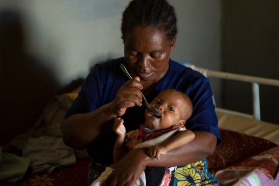 A woman feeds therapeutic milk to a five-month old.
