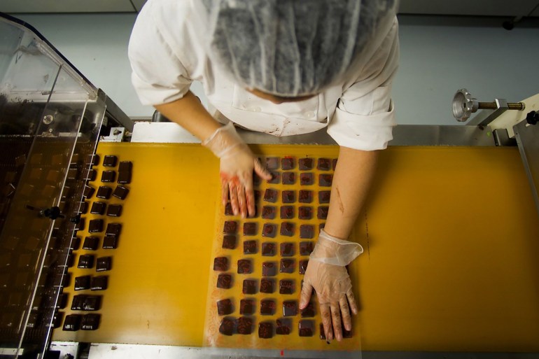 Chocolates come out of a machine after receiving a coating at a factory in Brooklyn, New York