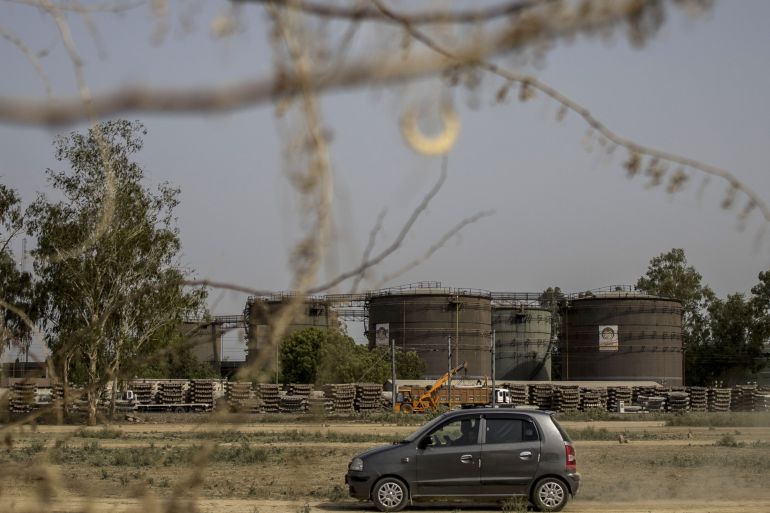 A car passes by an oil depot in New Delhi, India