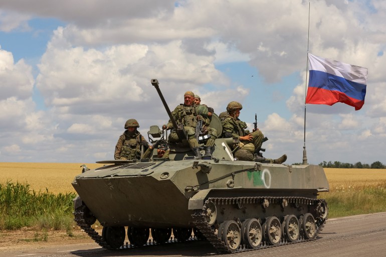 Russian troops ride on top an armoured vehicle in Russian-held part of Zaporizhia region, Ukraine, July 23, 2022