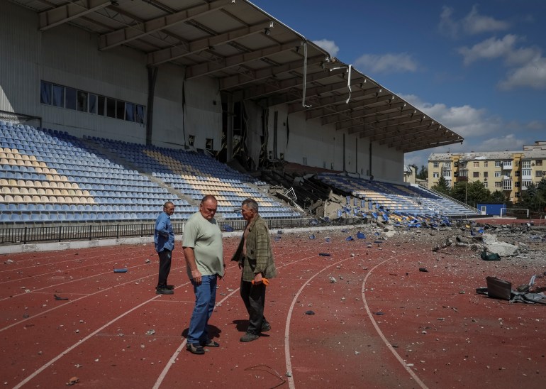 Employees stand at a stadium damaged by a Russian military attack in Bakhmut, Ukraine.