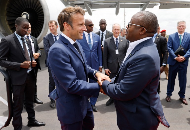 French President Emmanuel Macron (L) greets Guinea-Bissau's President Umaro Sissoco Embalo before leaving at Bissau's airport, on July 28, 2022 after a three-day African tour in Cameroon, Benin and Guinea-Bissau. (Photo by Ludovic MARIN / AFP)