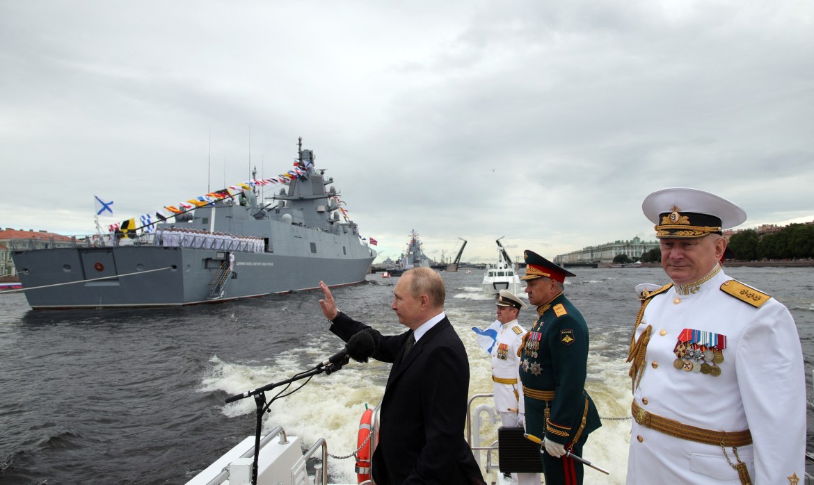 Russia's President Vladimir Putin (L) waves next to Russia's Defence Minister Sergei Shoigu (C) and Commander-in-Chief of the Russian Navy, Admiral Nikolai Yevmenov (R) as he takes part in the main naval parade marking the Russian Navy Day, in St. Petersburg