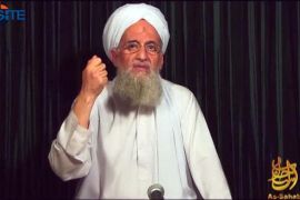 Ayman al-Zawahiri in white clothing and turban gesturing with his hand.