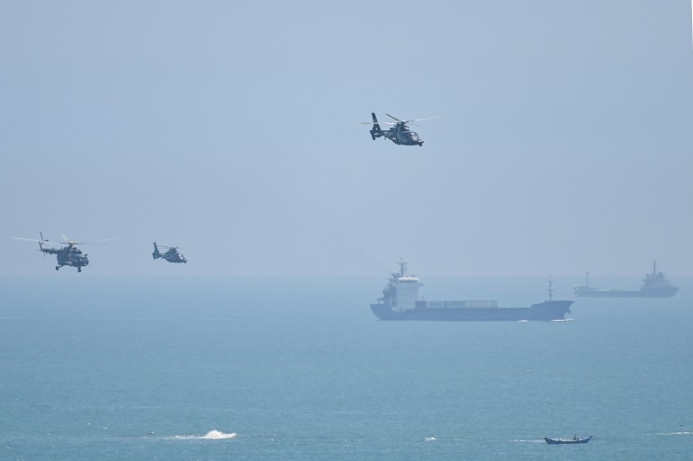 Three Chinese helicopters in the air with what look like commercial shipping vessels below off China's Pingtan island