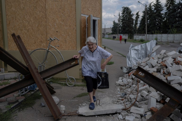 An elderly woman is seen making her way through rubble in eastern Ukraine's Donetsk region