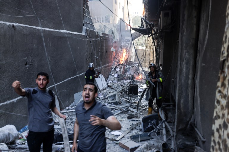 구조대원과 소방관은 2022년 8월 5일 이스라엘의 가자 시티에 대한 공습으로 파괴된 가운데 화재를 진압했습니다. - 이스라엘 군은 오늘 가자에 공습을 시작했다고 밝혔습니다. [Mohammed Abed/AFP]