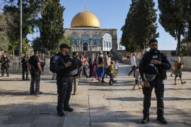 Israeli security forces protect a group of Jewish settler visitors as they walk past the Dome of the Rock mosque at the Al-Aqsa compound in Jerusalem, on August 7, 2022