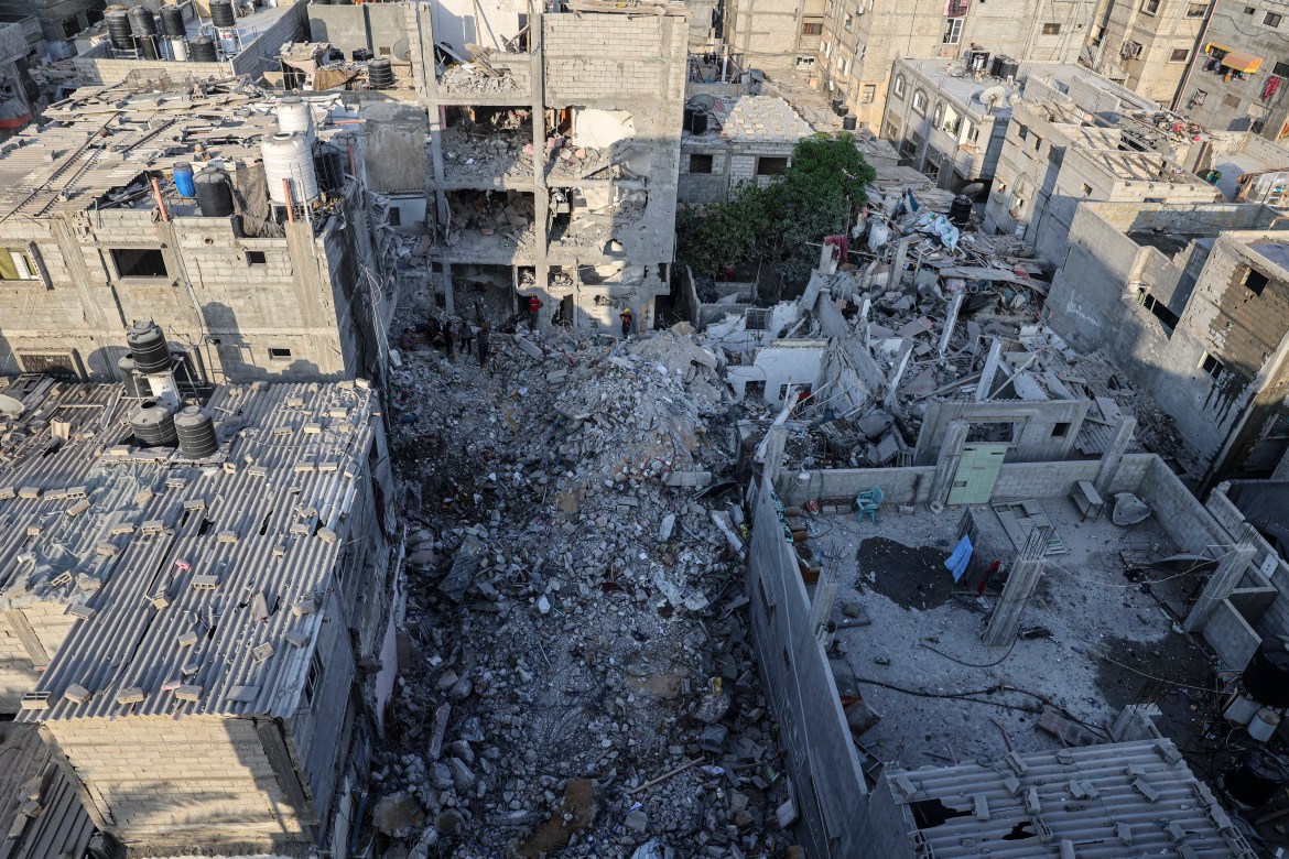 Palestinians search through the rubble of a building