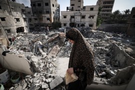 A woman walks through the rubble of a building destroyed in the latest Israeli bombardment in Gaza [Mahmud Hams/AFP] (AFP)